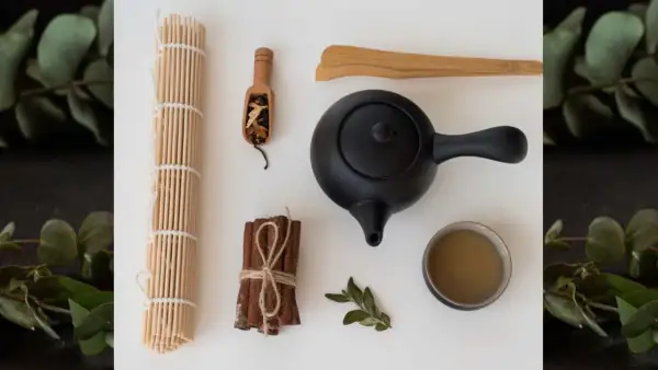 Akcesoria do parzenia herbaty, w tym czajniczek i filiżanka, obok cynamonu i liści. Warto znać herbata pu-erh przeciwwskazania.