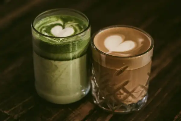 Zielone matcha latte i kawowe latte z serduszkami na piance. Dylemat: kawa czy herbata?